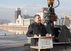 Verkehrsminister Christian Bernreiter steht an einem Rednerpult mit der Aufschrift "30 Jahre Main-Donau-Kanal". Im Hintergrund eine große Baggerschaufel und Hafengebäude