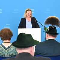 Staatsministerin Kerstin Schreyer am Mikrofon. Im Publikum sind von hinten einige Geehrte in Tracht zu erkennen