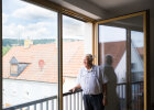 Ein älterer Mann steht an einem geöffneten, barrierefreien Fenster und blickt in die Iphöfer Altstadt.